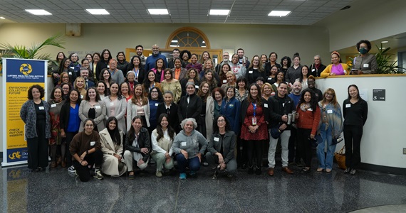 Members of the Latino Health Collective gather for a photo outside of George D. Behrakis Grand Hall.